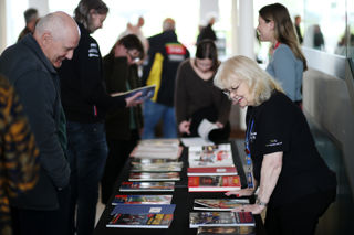 Volunteer showcasing Race Programmes from the Archive to Museum Visitors